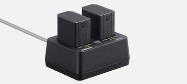 Hình ảnh sản phẩm hiển thị mặt trước bên trái của bộ sạc với hai pin NP-SA100 được lắp vào.
